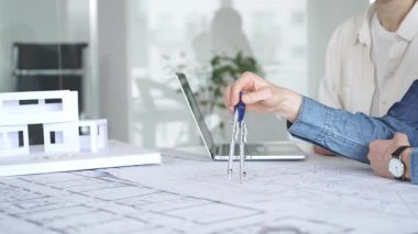 Mimarlar tasarım üzerinde işbirliği yapıyor, modern ofis ortamında planlar ve mimari modelleri tartışıyor, inşaat planlama ve mühendislik projelerinin geliştirilmesine odaklanıyor