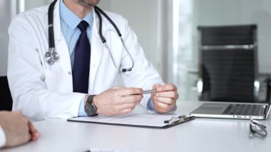 Beyaz önlüklü ve steteskop hastası olan bir doktor profesyonel ofis ortamında sağlık bilgileri ve tedavi seçeneklerini açıklıyor. Tıp, sağlık ve bilim konsepti