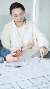 Mimarlar yeni bir yapı projesi geliştiriyor, tasarım detayları üzerinde işbirliği yapıyor ve tartışıyorlar, planlar, ölçekli bir model ve inşaatı planlamak için araçlar kullanıyorlar