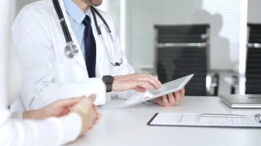 Doktorun hastaya danışması, bir klinik masasında tablet kullanması modern tıp ve dijital sağlık hizmetleri teşhisini sembolize ediyor. Tıp, sağlık ve bilim konsepti