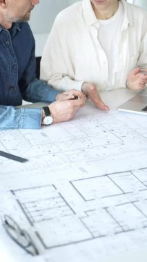 Mimarlar yeni bir yapı projesi geliştiriyor, tasarım detayları üzerinde işbirliği yapıyor ve tartışıyorlar, planlar, ölçekli bir model ve inşaatı planlamak için araçlar kullanıyorlar