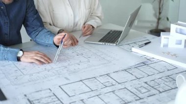 Mimarlar ve mühendisler bir geliştirme projesi üzerinde işbirliği yapıyorlar, fikirleri paylaşıyorlar, bina planlarını gözden geçiriyorlar ve gelecekteki inşaatların tasarım kavramlarını kesinleştirmek için bir yerleşim modelini tartışıyorlar.