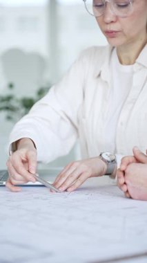 Bir proje üzerinde işbirliği yapan mimarlar, teknik çizimler ve ölçek modelini analiz ederek, mühendislik ve kentsel planlama alanlarında takım çalışması ve profesyonel uzmanlık sergileyerek,