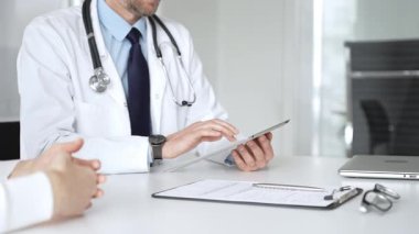 Doktorun hastaya danışması, bir klinik masasında tablet kullanması modern tıp ve dijital sağlık hizmetleri teşhisini sembolize ediyor. Tıp, sağlık ve bilim konsepti