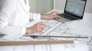 Mimarın elleri ayrıntılı planlar üzerinde ölçüm ve çizim yaparken, yeni yapılar için kavramsal tasarımlar yaratırken aynı zamanda mimari planlama sürecine yardımcı olmak için bir dizüstü bilgisayar kullanıyor.