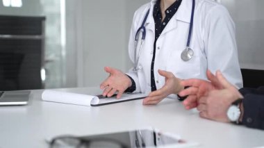 Beyaz önlüklü doktor, bir hastayla tıbbi istişare sırasında panoya notlar yazarak sağlık ve tedaviyi tartışıyor. Tıp, sağlık ve bilim konsepti