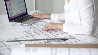 Mimarın elleri ayrıntılı planlar üzerinde ölçüm ve çizim yaparken, yeni yapılar için kavramsal tasarımlar yaratırken aynı zamanda mimari planlama sürecine yardımcı olmak için bir dizüstü bilgisayar kullanıyor.