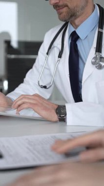 Doktorun hastaya danışması, bir klinik masasında tablet kullanması modern tıp ve dijital sağlık hizmetleri teşhisini sembolize ediyor. Tıp, sağlık ve bilim konsepti