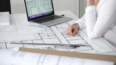 Mimarın elleri ayrıntılı planlar üzerinde ölçüm ve çizim yaparken, yeni yapılar için kavramsal tasarımlar yaratırken aynı zamanda mimari planlama sürecine yardımcı olmak için bir dizüstü bilgisayar kullanıyor.