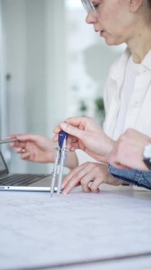 Bir proje üzerinde işbirliği yapan mimarlar, teknik çizimler ve ölçek modelini analiz ederek, mühendislik ve kentsel planlama alanlarında takım çalışması ve profesyonel uzmanlık sergileyerek,