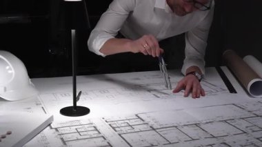 Mimarın dikkatle planladığı planlar bir masada, odaklanmış bir ortamda yapısal mühendislik projeleri tasarlıyor..