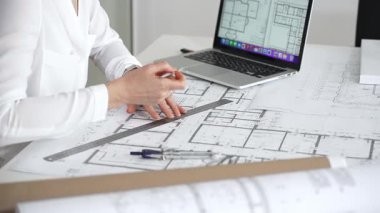 Mimarın elleri ayrıntılı planlar üzerinde ölçüm ve çizim yaparken, yeni yapılar için kavramsal tasarımlar yaratırken aynı zamanda mimari planlama sürecine yardımcı olmak için bir dizüstü bilgisayar kullanıyor.