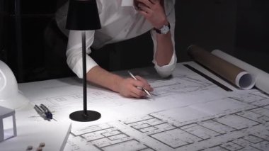 Çok çalışan mimar gece yarısı çalışırken baş ağrısı ve stres hissederek inşaat planları ve tasarım yapmayı planlıyor..