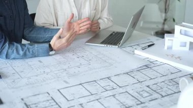 Mimarlar ve mühendisler bir geliştirme projesi üzerinde işbirliği yapıyorlar, fikirleri paylaşıyorlar, bina planlarını gözden geçiriyorlar ve gelecekteki inşaatların tasarım kavramlarını kesinleştirmek için bir yerleşim modelini tartışıyorlar.