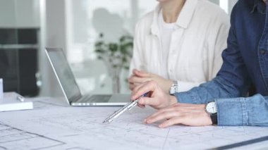 Mimarlar tasarım üzerinde işbirliği yapıyor, modern ofis ortamında planlar ve mimari modelleri tartışıyor, inşaat planlama ve mühendislik projelerinin geliştirilmesine odaklanıyor