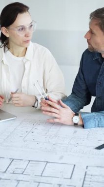 Mimarlar yeni bir yapı projesi geliştiriyor, tasarım detayları üzerinde işbirliği yapıyor ve tartışıyorlar, planlar, ölçekli bir model ve inşaatı planlamak için araçlar kullanıyorlar