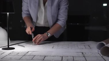 Bir planı ölçmek için cetvel kullanan kadın mimar, mimari planlar ve gelişim üzerine geç saatlere kadar masa lambası altında çalışıyor. İş ve mimarlık kavramı