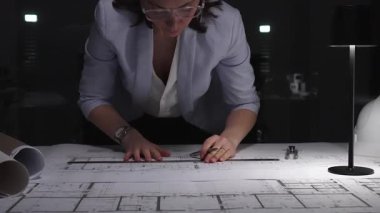 Kadın mimar ya da mühendis gece lambası altında cetvel ve kalem kullanarak mimari planlar çiziyor. İş ve mimarlık kavramı