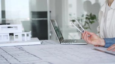 Mimarlar tasarım üzerinde işbirliği yapıyor, modern ofis ortamında planlar ve mimari modelleri tartışıyor, inşaat planlama ve mühendislik projelerinin geliştirilmesine odaklanıyor