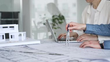 Mimarlar tasarım üzerinde işbirliği yapıyor, modern ofis ortamında planlar ve mimari modelleri tartışıyor, inşaat planlama ve mühendislik projelerinin geliştirilmesine odaklanıyor