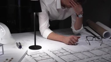 Çok çalışan mimar gece yarısı çalışırken baş ağrısı ve stres hissederek inşaat planları ve tasarım yapmayı planlıyor..