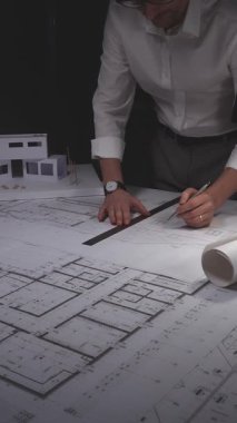 Ayrıntılı planlar ve mimari modeller üzerinde çalışan mimar, yeni bina planları ve tasarıma odaklanıyor. Gösterişsiz ışıklandırmada mimari ve iş kavramı
