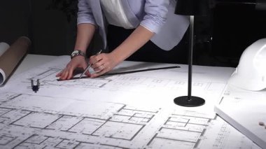 Ayrıntılı bina planları üzerinde çalışan, cetvelle planlar üzerinde ölçüm yapan, yeni yapıları kavramsallaştıran kadın mimar. İş ve mimarlık kavramı