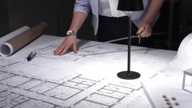 Ayrıntılı bina planları üzerinde çalışan, cetvelle planlar üzerinde ölçüm yapan, yeni yapıları kavramsallaştıran kadın mimar. İş ve mimarlık kavramı