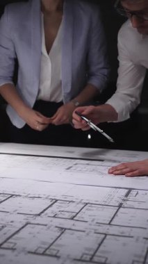 Mimarlar ve mühendisler, bina veya inşaat tasarımlarını ölçmek ve geliştirmek için bir pusula kullanarak plan üzerinde işbirliği yapıyorlar. Gösterişsiz ışıklandırmada mimari ve iş kavramı