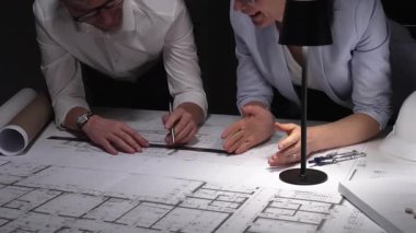 Mimarlar birlikte çalışır, bina planlarını ve planlarını analiz eder, bir ofiste tasarım kavramlarını ve mühendislik unsurlarını tartışırlar..