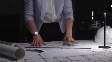 Profesyonel mimar mimari planlar tasarlıyor, masa lambasının altına çizgiler çiziyor, hassasiyet ve adanmışlığı vurguluyor