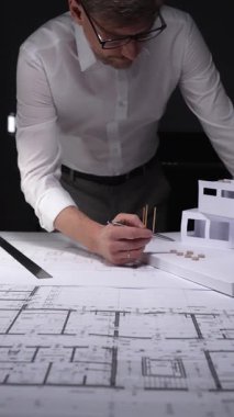 Profesyonel mimar bir inşaat projesi tasarlıyor. Mühendis bir konut modeli yaratıyor ve detaylı kat planlarını gözden geçiriyor. Gösterişsiz ışıklandırmada mimari ve iş kavramı