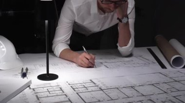 Çok çalışan mimar gece yarısı çalışırken baş ağrısı ve stres hissederek inşaat planları ve tasarım yapmayı planlıyor..