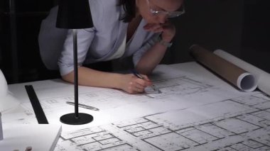 İşteki bıkkınlık ve yorgunluğu ifade eden, loş ofisteki mimari planları gözden geçiren profesyonellerin şaşkına dönmüş. İş ve mimarlık kavramı