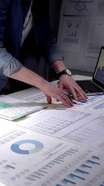 Finansal raporları, çizelgeleri ve hesap tablolarını inceleyen eller iş lambası ve dizüstü bilgisayarla beyaz bir masa üzerinde, iş planlama, bütçe ve yatırım kararları için gece yarısı odaklı analizler