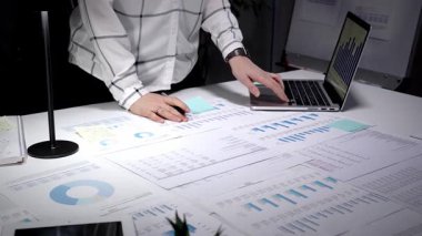 İşadamı karanlık bir ofisteki bir masaya odaklanmış, dizüstü bilgisayardaki mali raporları ve çizelgeleri analiz ediyor, gece yarısı üretkenlik oturumunda iş akışını yönetiyor.