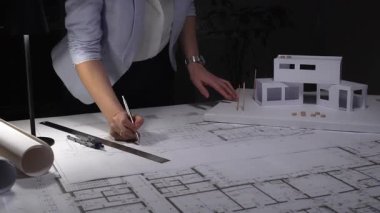 Mimarlar, masanın üzerinde modern ev ölçeğinde bir modelle inşaat planları ve mimari çizimler üzerinde çalışıyorlar, tasarım planlıyorlar. İş ve mimarlık kavramı