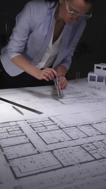 Kadın mimar, tasarım ve planlama üzerine yoğunlaşarak yeni bir konut projesinin mimari planlarını ayrıntılı olarak hazırladı. Gösterişsiz ışıklandırmada mimari ve iş konsepti