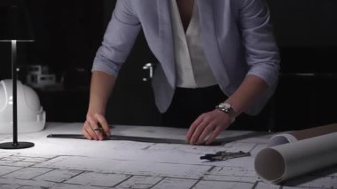 Profesyonel mimar mimari planlar tasarlıyor, masa lambasının altına çizgiler çiziyor, hassasiyet ve adanmışlığı vurguluyor