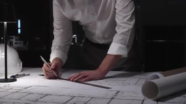 Mimar, bir cetvel ve kalemle detaylı bina planları çizerek mühendislik tasarımı ve inşaat geliştirmesine odaklanıyor. İş ve mimarlık kavramı
