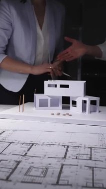 Mimarlar konut tasarımı projesinde işbirliği yapıyorlar, mimari planlardan minyatür bir kağıt ev modeli inşa ediyorlar. Gösterişsiz ışıklandırmada mimari ve iş kavramı