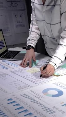 Profesyonel kadın gece geç saatlere kadar çalışıyor, iş raporlarını, mali verileri ve piyasa stratejisini analiz ediyor, masa lambası aydınlatması altında bir kalemle kapsamlı evrak işlerini tamamlıyor.