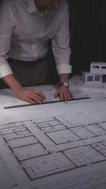Ayrıntılı planlar ve mimari modeller üzerinde çalışan mimar, yeni bina planları ve tasarıma odaklanıyor. Gösterişsiz ışıklandırmada mimari ve iş kavramı