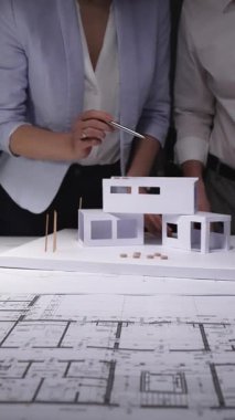 Mimarlar konut inşaatı tasarlar, ofis masasında kağıt modelli planlar analiz ederler, inşaat projesini geliştirirler. Mimarlık ve iş kavramı gösterişsiz ışıklandırmada