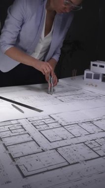 Kadın mimar, tasarım ve planlama üzerine yoğunlaşarak yeni bir konut projesinin mimari planlarını ayrıntılı olarak hazırladı. Gösterişsiz ışıklandırmada mimari ve iş konsepti