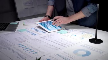 Finansal raporları, çizelgeleri ve hesap tablolarını inceleyen eller iş lambası ve dizüstü bilgisayarla beyaz bir masa üzerinde, iş planlama, bütçe ve yatırım kararları için gece yarısı odaklı analizler