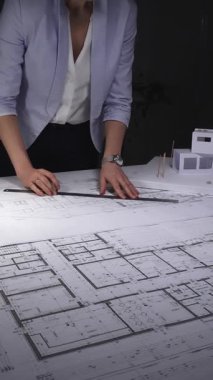 Mimari planlar ve ölçekli modeller üzerinde çalışan kadın mimar, inşaat planlama ve mühendisliğe odaklanıyor. Gösterişsiz ışıklandırmada mimari ve iş konsepti