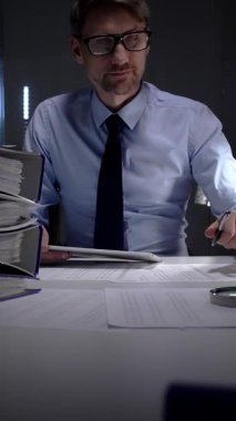 İş adamı geç saatlere kadar çalışıyor, karanlık bir ofiste masasında önemli evrakları imzalıyor, teslim tarihleri ve sorumluluklarına odaklanıyor. İş dünyasında denetim ve vergi teması