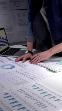 Finansal raporları, çizelgeleri ve hesap tablolarını inceleyen eller iş lambası ve dizüstü bilgisayarla beyaz bir masa üzerinde, iş planlama, bütçe ve yatırım kararları için gece yarısı odaklı analizler