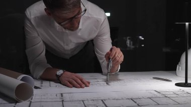 Mimar gece bina planları tasarlıyor, yeni bir inşaat projesi için fazla mesai yapıyor. Çalışma alanı, planlar, çizim araçları ve modern ofis ışıklandırması. Mimarlık, mühendislik kavramı